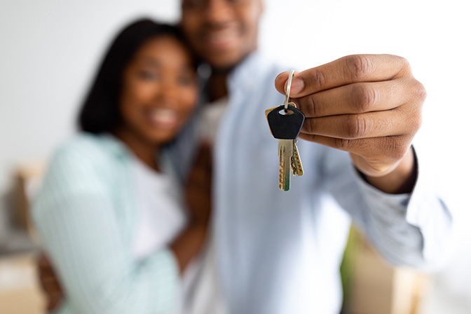 Black couple holding up house keys.