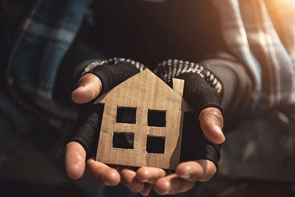 Hands holding a cardboard cutout of a house.